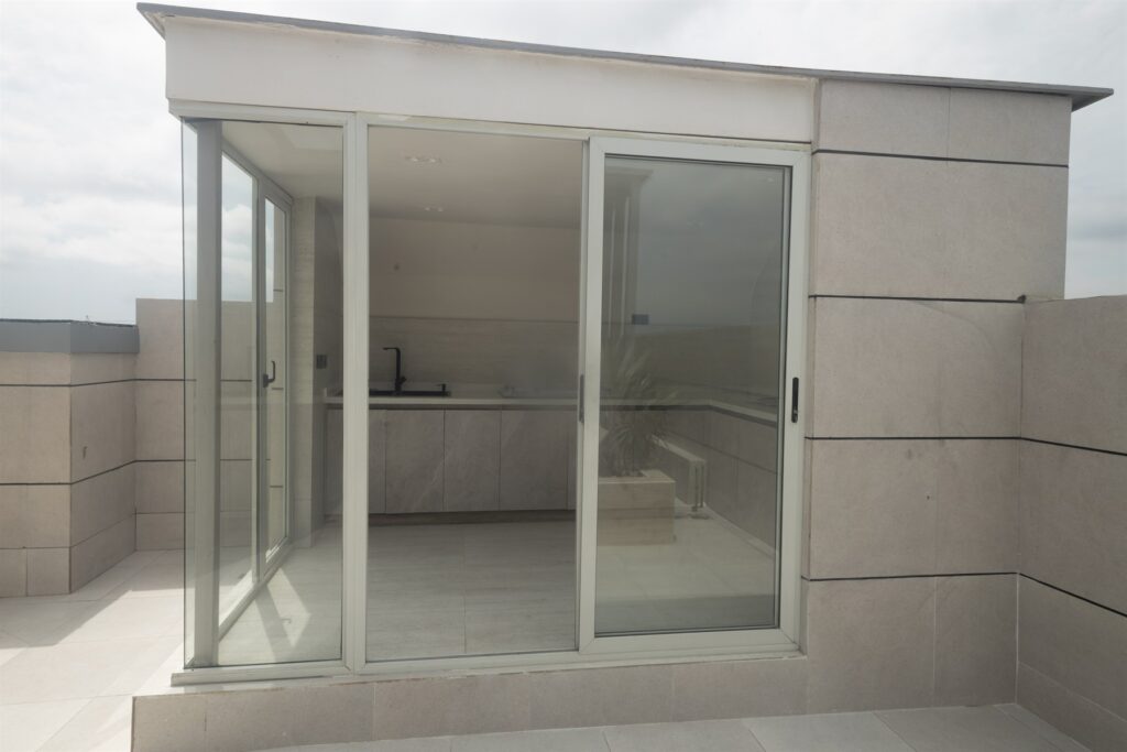 Brum Height 6: Glass-enclosed rooftop room opening onto the terrace